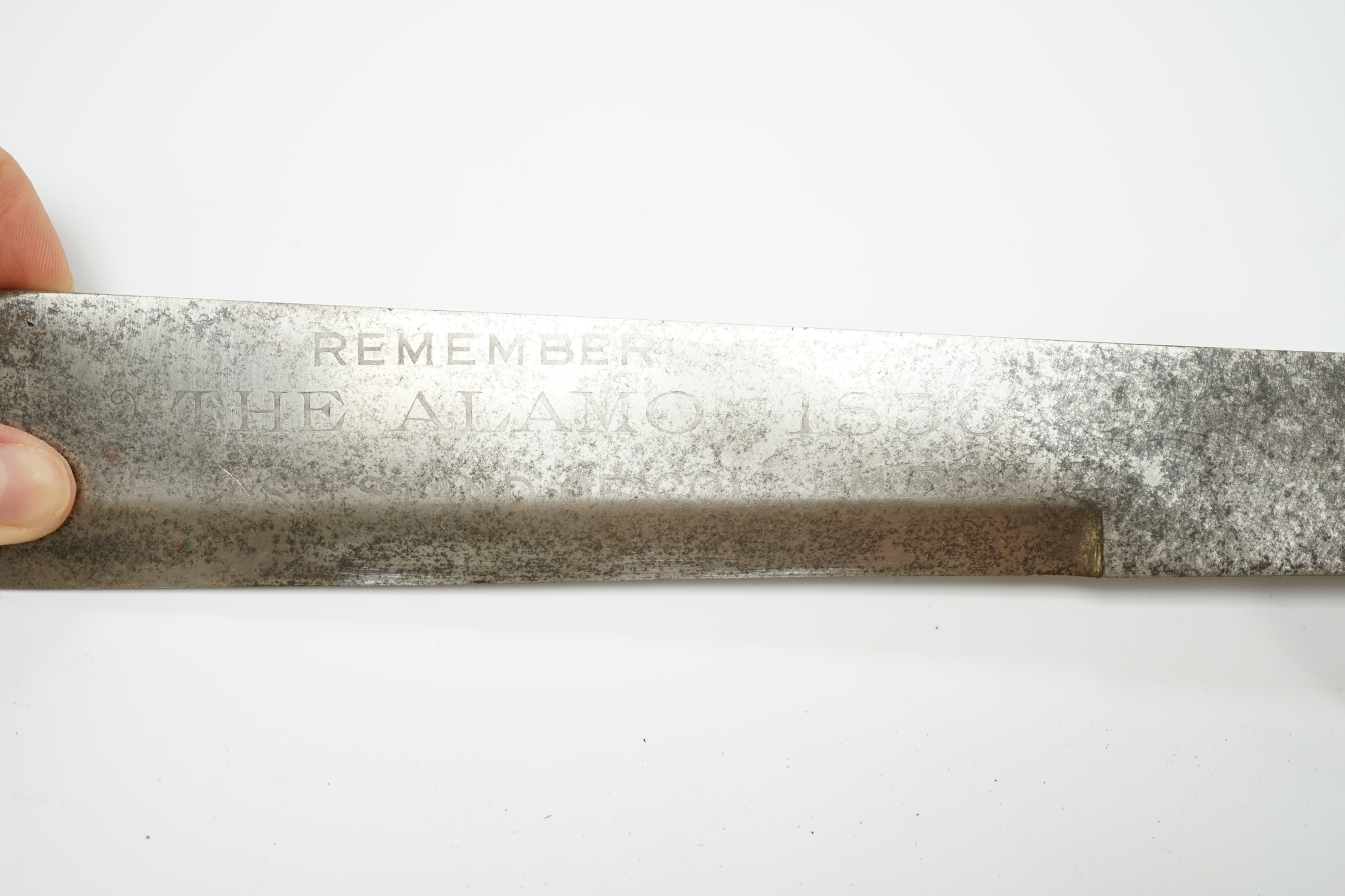 A Bowie knife with swollen blade, etched ‘Remember the Alamo 1836 the last stand of Col. Jim Bowie’, brass cross piece, riveted rosewood grips, blade length 27.5cm. Condition - fair